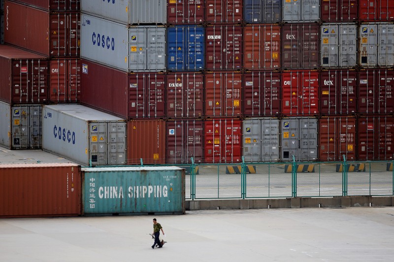 FILE PHOTO: A man walks past a container area at the Yangshan Deep Water Port, part of the newly announced Shanghai Free Trade Zone, south of Shanghai