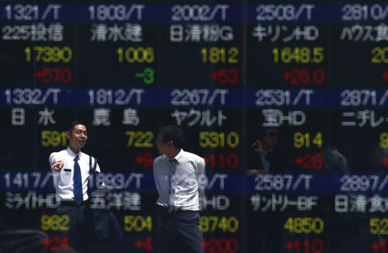 Men are refelcted in a screen displaying market indices outside a brokerage in Tokyo