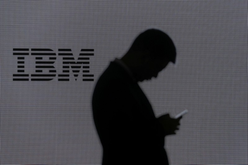 FILE PHOTO: A man checks his mobile phone outside IBM's booth at the Mobile World Congress in Barcelona