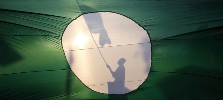 A supporter of opposition PAS is silhouetted on its giant flag as he campaigns on a street in Pekan