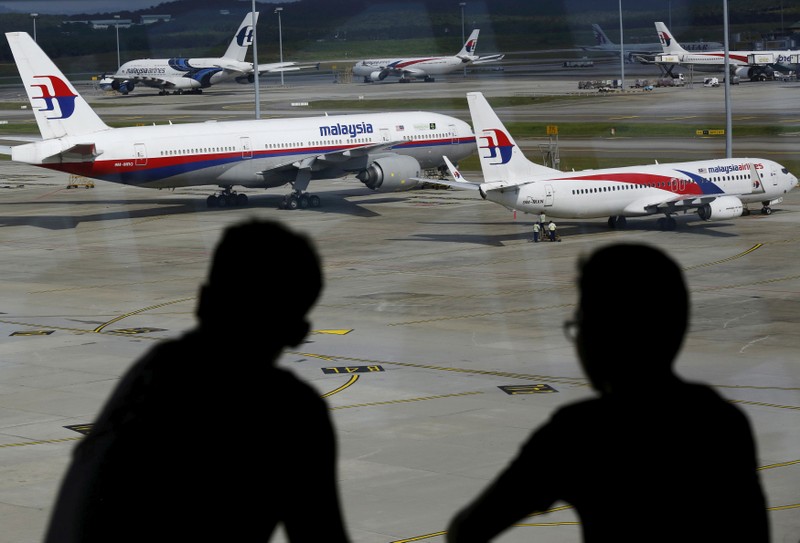 FILE PHOTO: Men watch Malaysia Airlines aircraft at Kuala Lumpur International Airport in Sepang, Malaysia