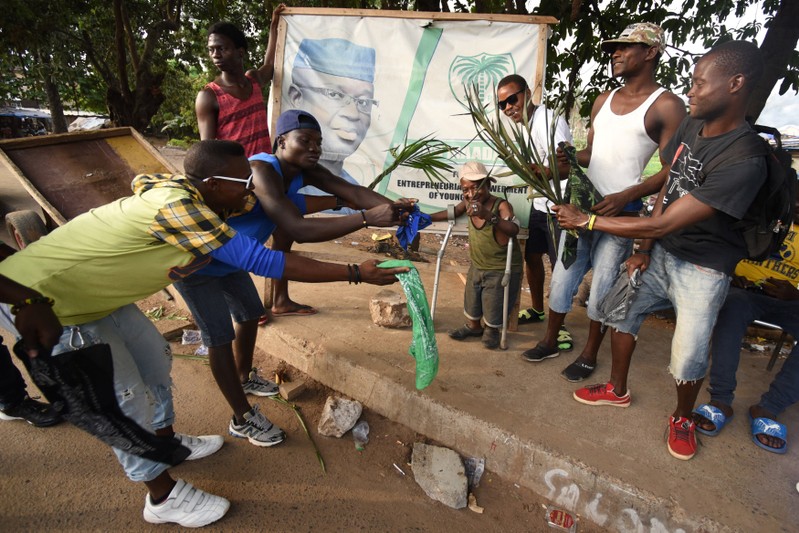 Sierra Leone People's Party (SLPP) supporters react near a poster depicting Julius Maada Bio, the presidential candidate for the (SLPP) in Freetown