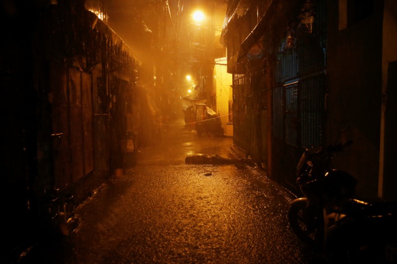 Heavy rain pours as the body of a man, killed by unidentified gunmen riding motorcycles, is left in a narrow alley in Manila