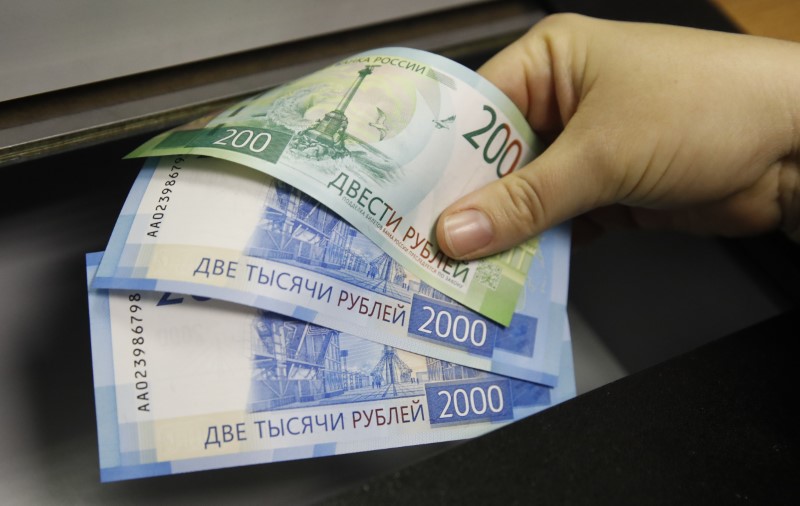 A woman holds new 200 and 2,000 rouble banknotes in a bank in Moscow