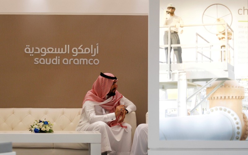 FILE PHOTO: A Saudi Aramco employee sits in the area of its stand at the Middle East Petrotech 2016 in Manama, Bahrain