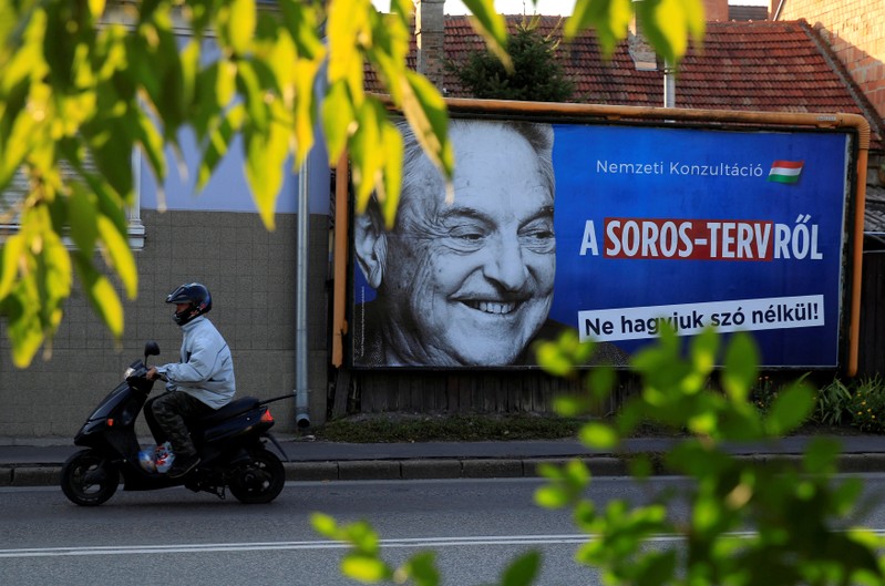 FILE PHOTO: A man rides his moped past a government billboard in Szolnok