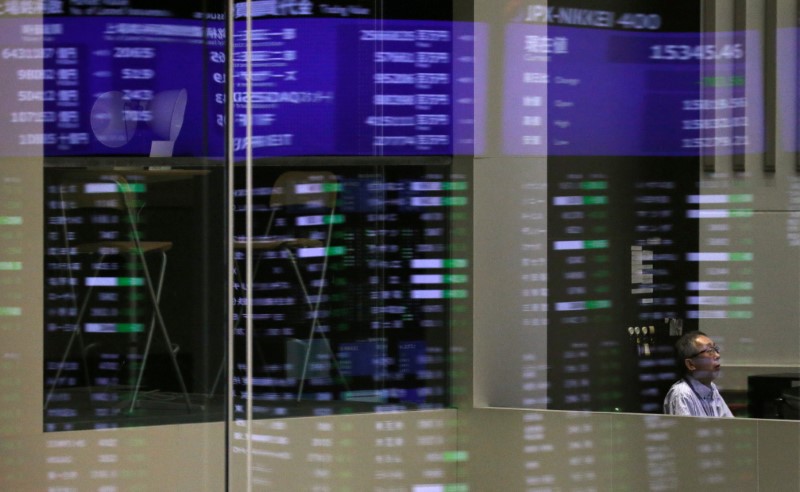 Market prices are reflected in a glass window at the TSE in Tokyo