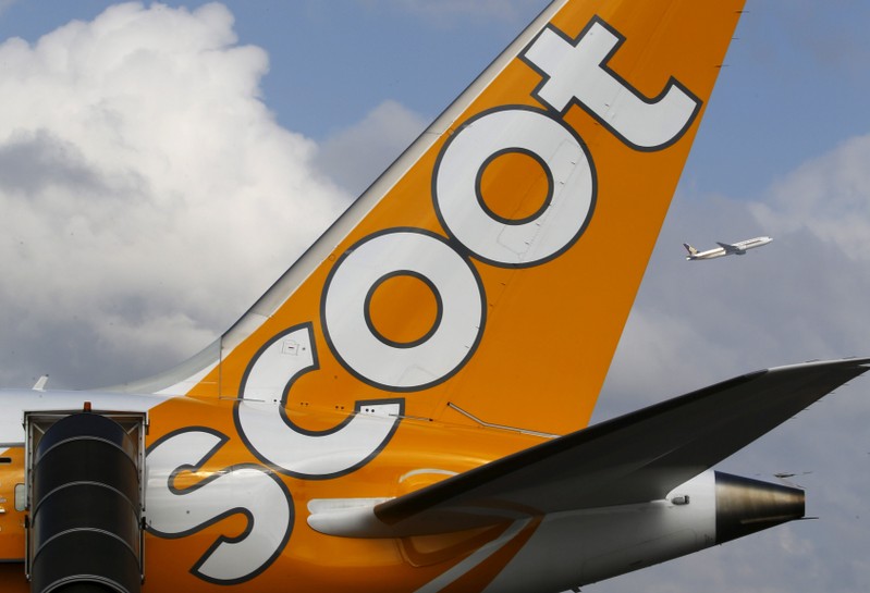 FILE PHOTO: A Singapore Airlines aircraft flies past a Scoot Boeing 787 Dreamliner displayed at the Singapore Airshow at Changi Exhibition Center