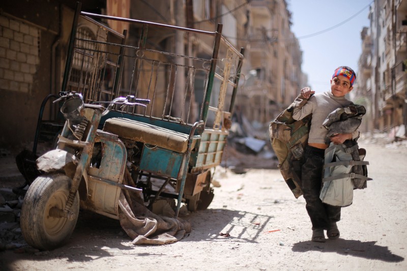 A boy walks along a damaged street at the city of Douma in Damascus