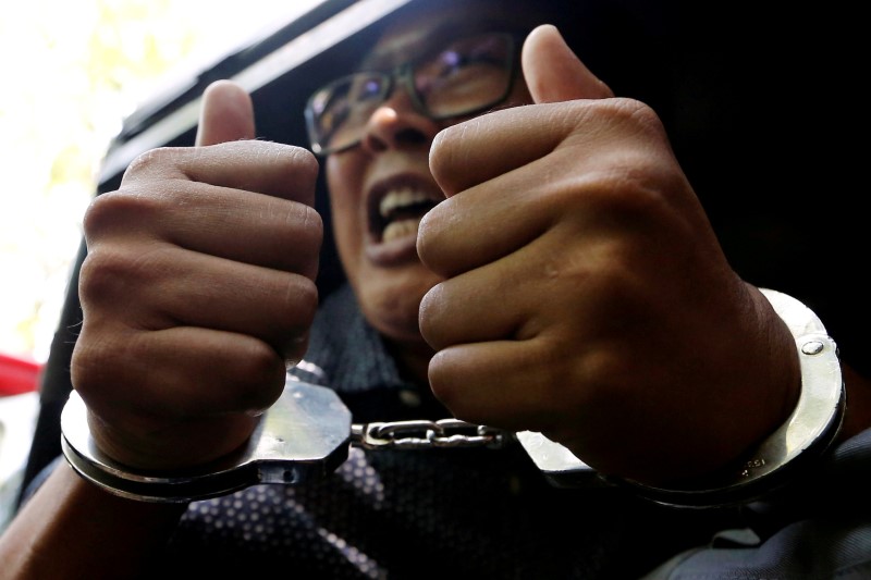 Detained Reuters journalist Wa Lone gestures to the media as he is escorted by police after a court hearing in Yangon