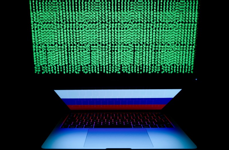Russian flag is seen on the laptop screen in front of a computer screen on which cyber code is displayed, in this illustration picture