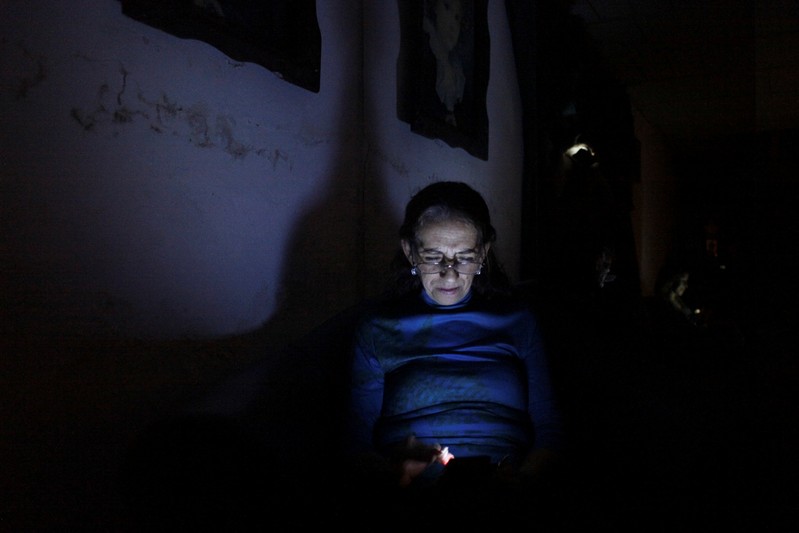 Carmenza Herrera uses her cellphone during a blackout in San Cristobal
