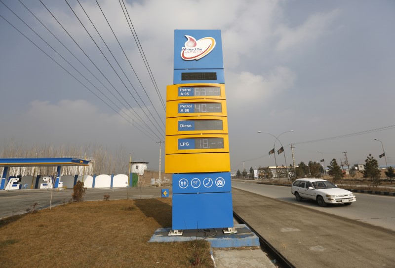 A car pasts behind a oil prices board d at Ahmad Yar Group fuel station shows on outskirt of Kabul