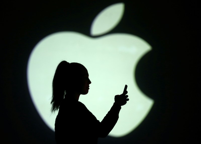 FILE PHOTO: Silhouette of mobile user is seen next to a screen projection of Apple logo in this picture illustration