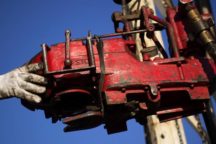 FILE PHOTO: A man works on the rig of an oil drilling pump site in McKenzie County outside of Williston