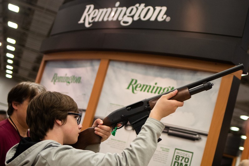 A boy aims a Remington firearm at the annual NRA meeting in Dallas, Texas
