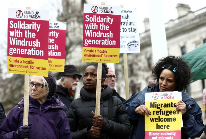 People hold placards during a demonstration to protest againt the treament of members of the Windrush generation, opposite the Houses of Parliament in London