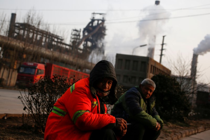 FILE PHOTO: Men sit outside a steel factory in Wu'an, Hebei province