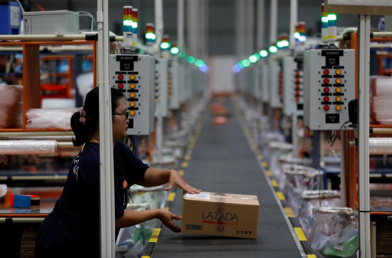 A worker places a package for delivery on a conveyor belt at online retailer Lazada's warehouse in Depok