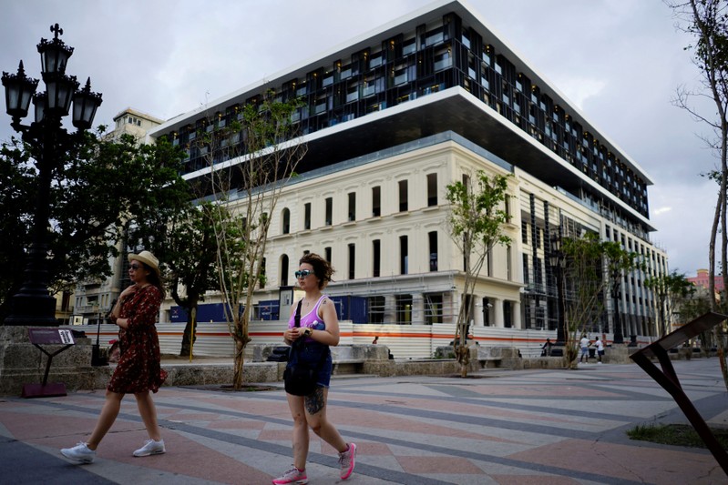 Tourists pass by a hotel under construction at the Paseo del Prado boulevard in Havana