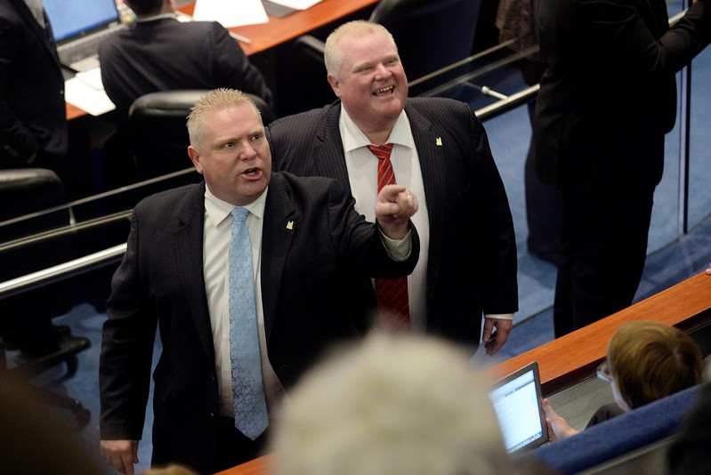 FILE PHOTO: Toronto city councillor Doug Ford and his brother, Mayor Rob Ford react to the gallery after the mayor and an unidentified member of his staff captured images of the gallery during a special council meeting at City Hall in Toronto