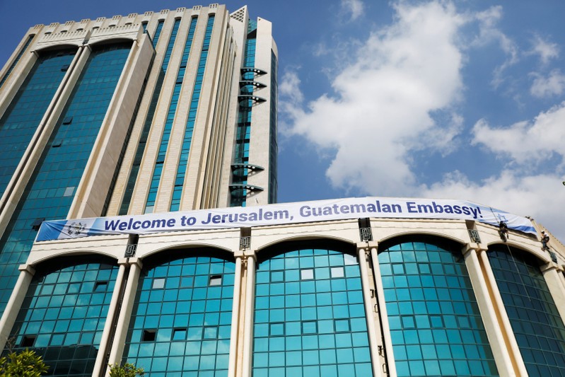 Workers hanging from the side of a building place a banner welcoming the opening of the new Guatemalan embassy in Jerusalem, in the complex hosting the new embassy in Jerusalem
