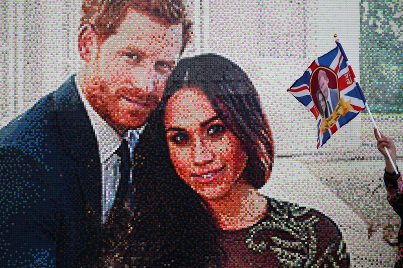 A girl waves a flag next to a LEGO brick mosaic of Britain's Prince Harry and Meghan Markle in Windsor