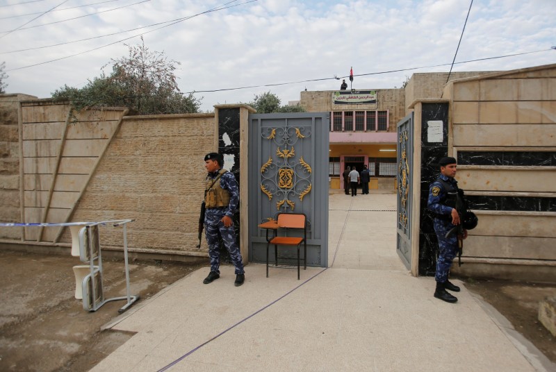 Iraqi security forces stand outside a polling station during the parliamentary election in Mosul