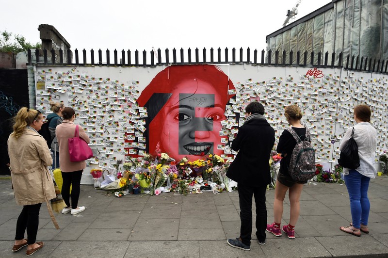People look on as messages and flowers are left at a memorial to Savita Halappanavar a day after an Abortion Referendum to liberalise abortion laws was passed by popular vote, in Dublin