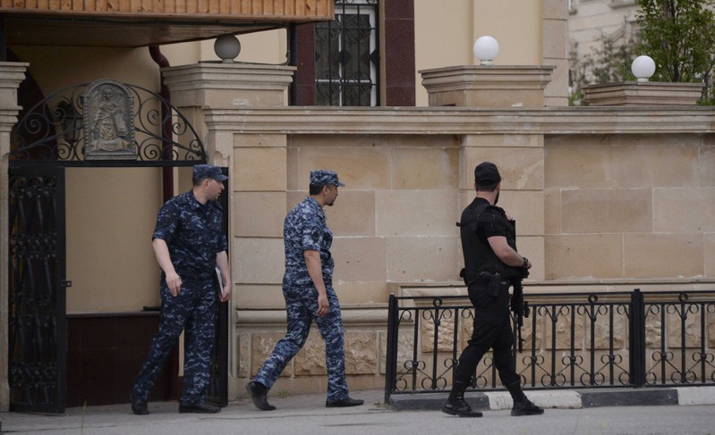 Law enforcement officers walk outside an Orthodox church after the attack of militants in Grozny