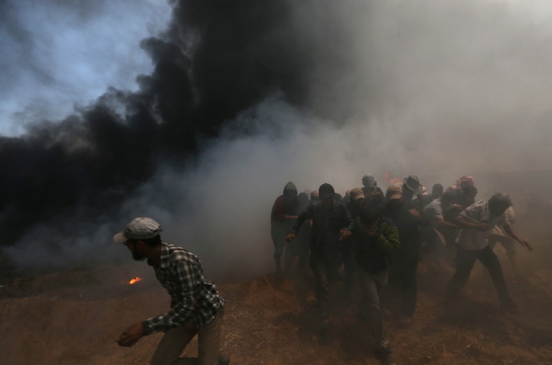 Palestinian demonstrators run for cover during a protest in the southern Gaza Strip