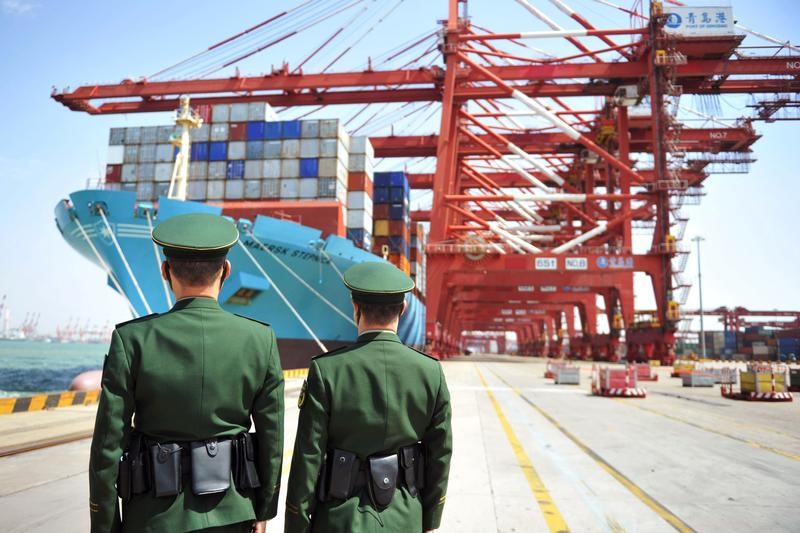 Police officers are seen in front of a cargo ship with containers at a port in Qingdao