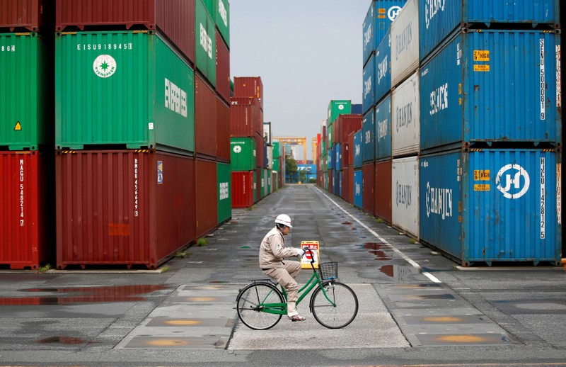 FILE PHOTO: A worker rides a bicycle in a container area at a port in Tokyo