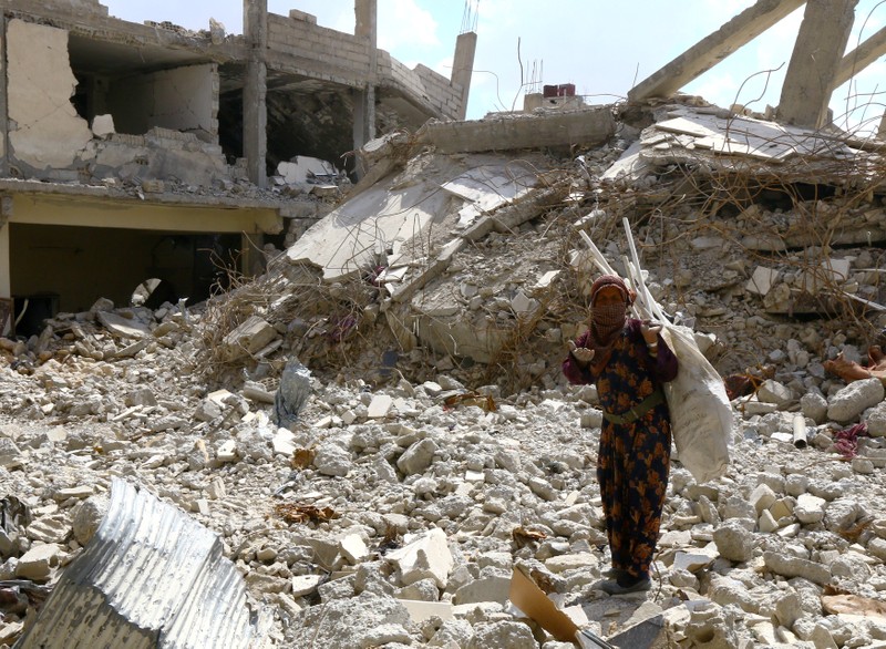 FILE PHOTO: A woman gestures as she stands on rubble of damaged buildings in Raqqa