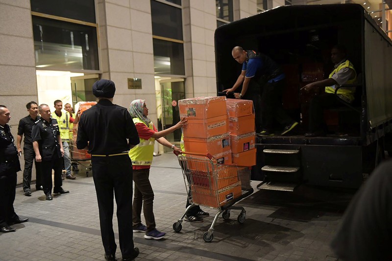 A Malaysian police officer pushes a trolley during a raid of three apartments in a condominum owned by former Malaysian prime minister Najib Razak’s family, in Kuala Lumpur