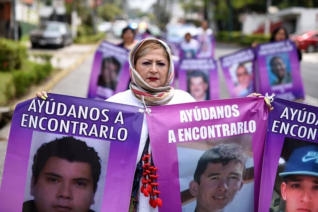 A woman holds banners with pictures of missing persons during a march to mark Women's Day in Xalapa