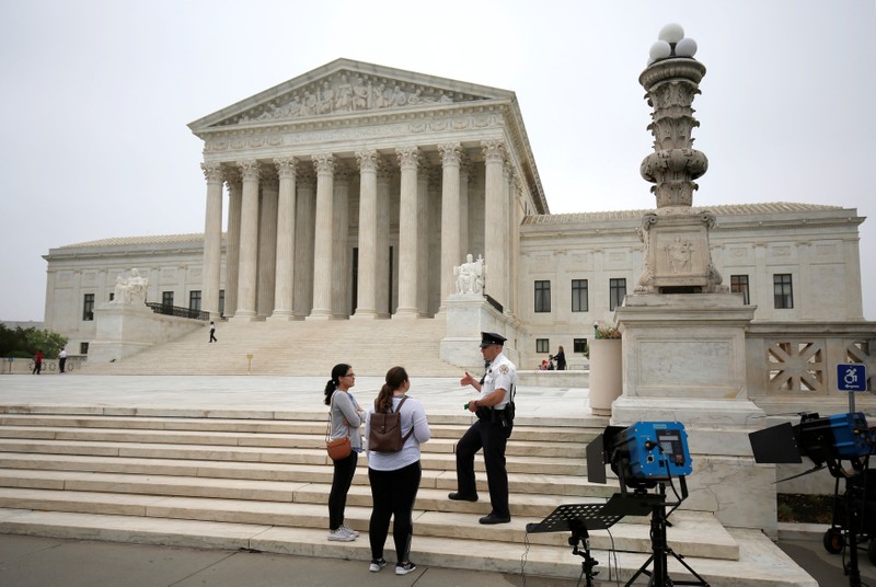 A police officer speaks with tourists before decisions are released at the Supreme Court in Washington