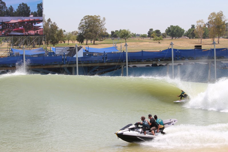 A wave-creating hydrofoil is seen behind a surfer riding an artificial wave at a practice session at World Surf League Surf Ranch in Lemoore, California, ahead of Founders' Cup