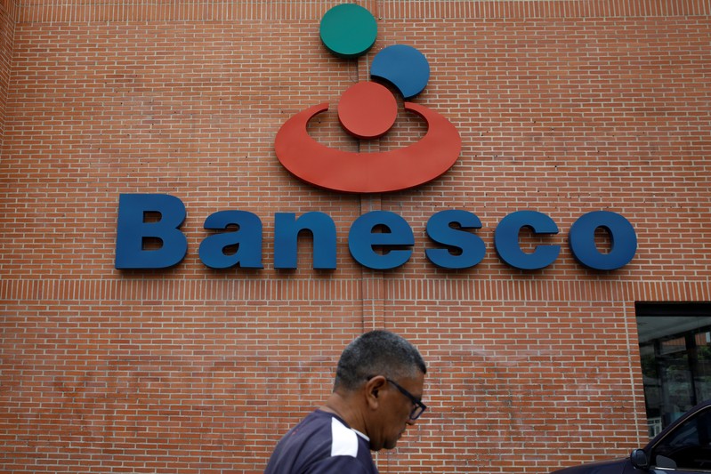 A man walks past the corporate logo of Banesco bank at one of its branches in Caracas
