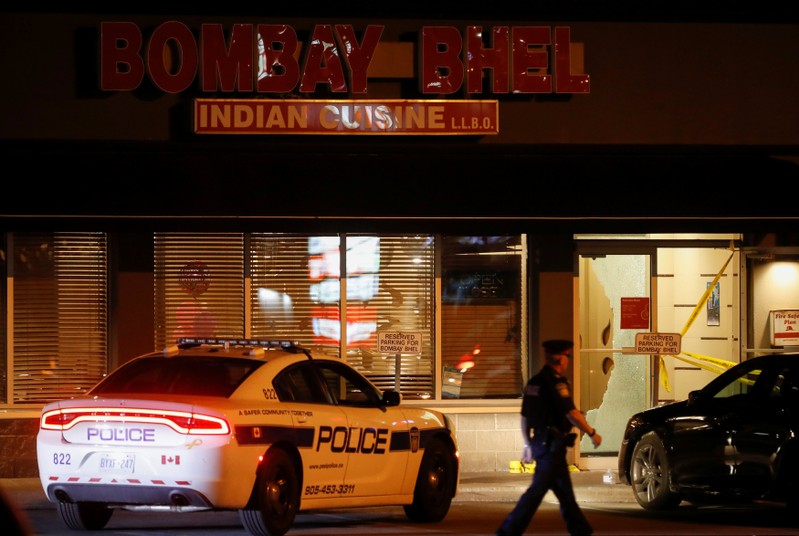 Police officer walks in front of Bombay Bhel restaurant, where two unidentified men set off a bomb, in Mississauga