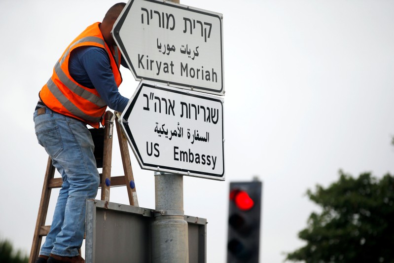 A worker hangs a road sign directing to the U.S. embassy, in the area of the U.S. consulate in Jerusalem