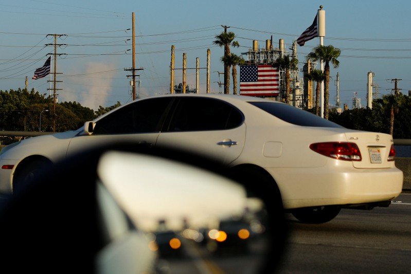 FILE PHOTO: Automobiles speed past an oil refinery as they travel down a major highway in Carson, California