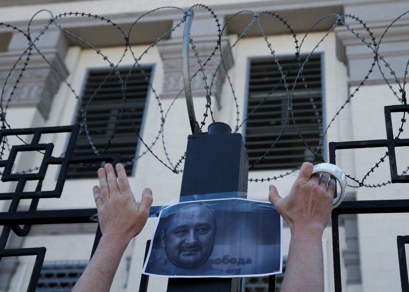 A man hangs a picture of Russian dissident journalist Babchenko, who was shot dead in the Ukrainian capital on May 29, on a fence of the Russian embassy in Kiev
