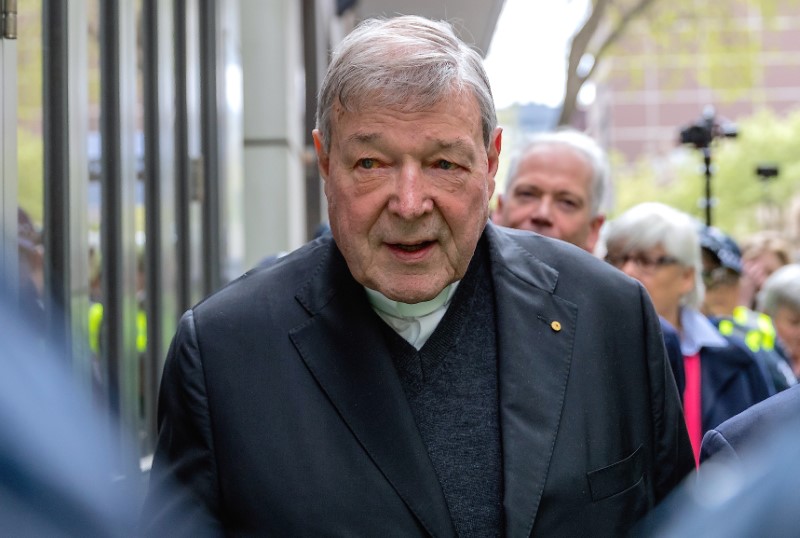 Vatican Treasurer Cardinal George Pell is surrounded by Australian police as he leaves the Melbourne Magistrates Court in Australia