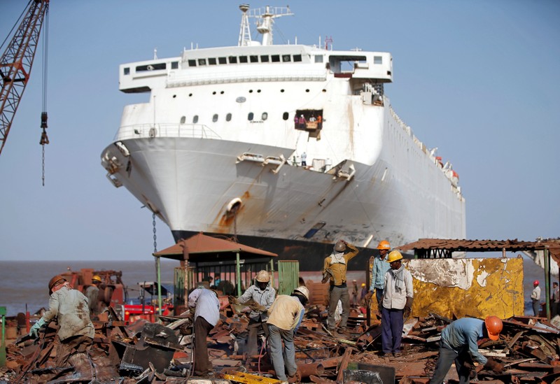 FILE PHOTO: Workers sort out scrap metal of a decommissioned ship at the Alang shipyard