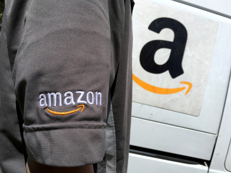 FILE PHOTO: An Amazon.com Inc driver stands next to an Amazon delivery truck in Los Angeles, California
