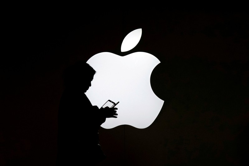 FILE PHOTO: A woman looks at the screen of her mobile phone in front of an Apple logo outside its store in Shanghai
