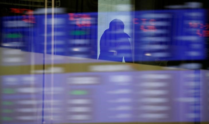 FILE PHOTO: A visitor is seen as market prices are reflected in a glass window at the TSE in Tokyo