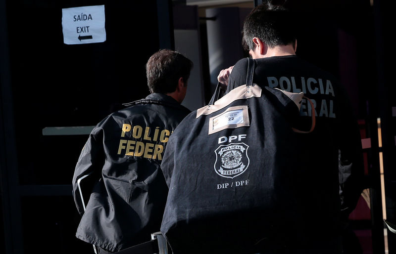 A federal police officer carries a pouch as he arrives at the Federal Police headquarters in Sao Paulo
