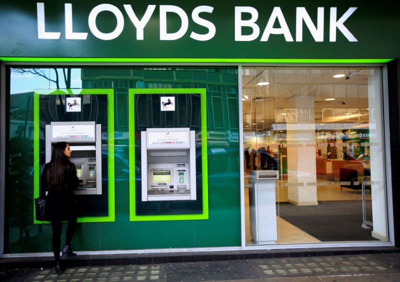 FILE PHOTO: A woman uses a cash machine at a Lloyds Bank branch in central London